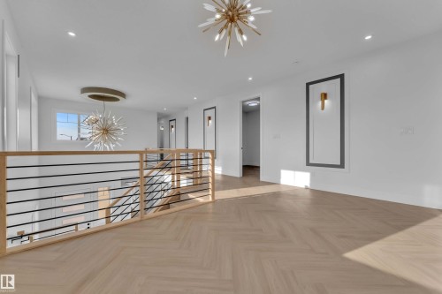 Herringbone wood-finish flooring, contemporary light fixtures, recessed lighting, and a modern horizontal railing system - 465 Crystal Creek Link, Leduc, AB - Indoor Photo Showing Other Room