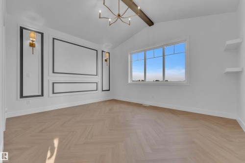 Herringbone wood-finish flooring, vaulted ceiling with exposed beam, decorative wall molding, modern chandelier, and built-in wall sconces - 465 Crystal Creek Link, Leduc, AB - Indoor Photo Showing Other Room