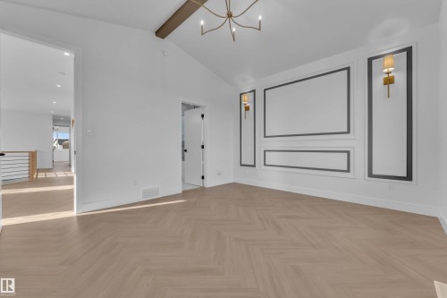 Vaulted ceiling with an exposed wood beam, decorative wall molding, herringbone wood-finish flooring, and a modern chandelier - 465 Crystal Creek Link, Leduc, AB - Indoor Photo Showing Other Room