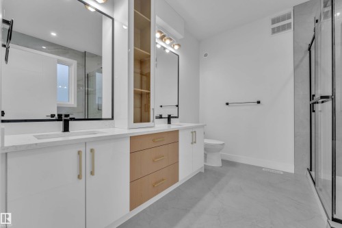Dual vanity with integrated sinks, quartz countertops, black-framed mirrors, and a glass-enclosed shower - 465 Crystal Creek Link, Leduc, AB - Indoor Photo Showing Bathroom