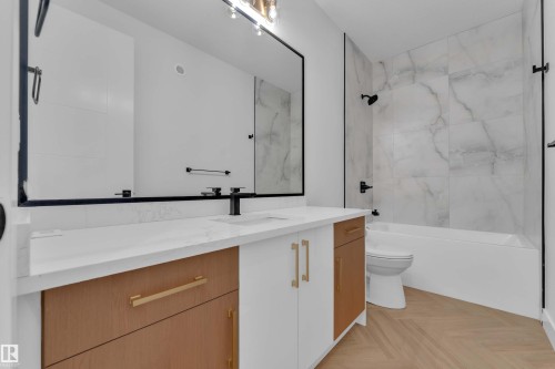 Bathroom featuring a vanity with wood-finish and white cabinetry, a rectangular sink, matte black faucet, and a large mirror - 465 Crystal Creek Link, Leduc, AB - Indoor Photo Showing Bathroom