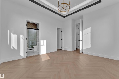 Herringbone wood-finish flooring, tray ceiling with recessed lighting, modern chandelier, white walls, and sleek black interior doors - 465 Crystal Creek Link, Leduc, AB - Indoor Photo Showing Other Room