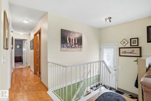 Upper level hallway featuring wood-finish flooring, light-toned walls, and multiple panel doors - 5702 52 Avenue, Beaumont, AB - Indoor Photo Showing Other Room