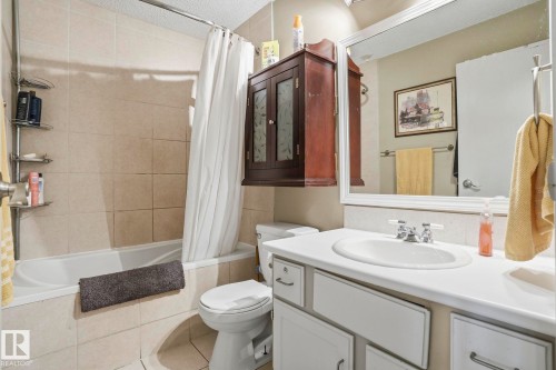 Bathroom featuring a white vanity with integrated sink, chrome faucet, and a framed mirror - 5702 52 Avenue, Beaumont, AB - Indoor Photo Showing Bathroom