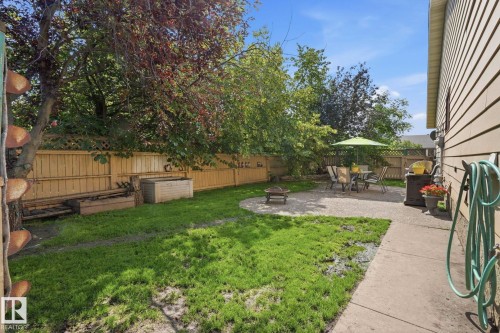 Private backyard featuring a concrete patio, perimeter wood fencing, and mature trees - 5702 52 Avenue, Beaumont, AB - Outdoor With Backyard
