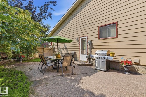 Rear exterior featuring a patio, light tan horizontal siding, and a white entry door with a storm door - 5702 52 Avenue, Beaumont, AB - Outdoor With Exterior