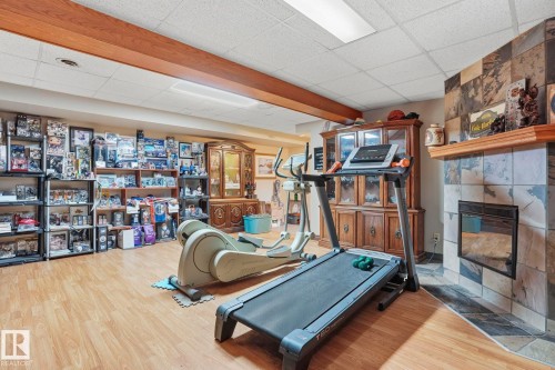 Spacious lower level featuring wood-finish flooring, a ceiling with exposed wood beam, and recessed lighting - 5702 52 Avenue, Beaumont, AB - Indoor Photo Showing Gym Room