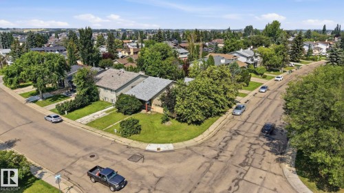 Suburban setting featuring an established residential street, mature trees, and a clear sky - 5702 52 Avenue, Beaumont, AB - Outdoor With View