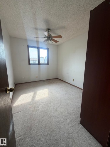 Bright bedroom featuring neutral carpeting, ceiling fan with integrated lighting, and large window with natural light - 9223 172 Avenue Nw, Edmonton, AB 