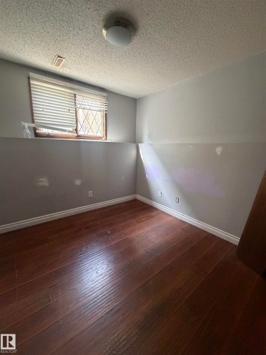 Wood-finish flooring with white baseboards, a flush-mount ceiling light fixture, and a window with blinds - 9223 172 Avenue Nw, Edmonton, AB 