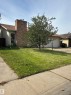 Brick chimney with a metal cap, attached garage with a white door, and a concrete driveway - 9223 172 Avenue Nw, Edmonton, AB 