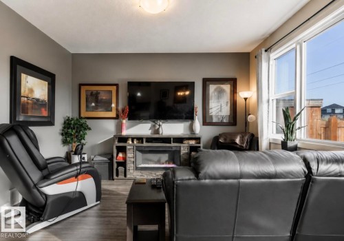 Recessed media console with an electric fireplace, wood-finish flooring, and large windows - 12737 205 Street Nw, Edmonton, AB - Indoor Photo Showing Living Room