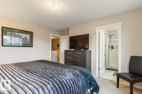 Wall-mounted light fixture, light gray wall color, dark wood-finish dresser, white paneled door, and a tiled shower stall - 12737 205 Street Nw, Edmonton, AB - Indoor Photo Showing Bedroom