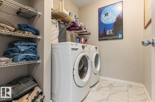 Laundry area featuring a side-by-side washer and dryer, wire shelving, and light-toned tile flooring - 12737 205 Street Nw, Edmonton, AB - Indoor Photo Showing Laundry Room