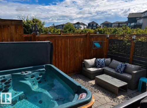 Private outdoor space featuring a hot tub, wood fencing, and a combination of paver stones and gravel hardscaping - 12737 205 Street Nw, Edmonton, AB - Outdoor