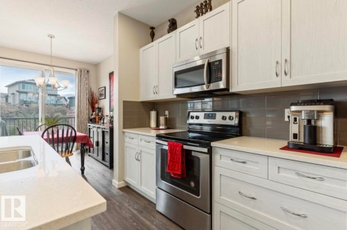 Kitchen featuring white cabinetry, stainless steel appliances, light-toned countertops, and a gray subway tile backsplash - 12737 205 Street Nw, Edmonton, AB - Indoor Photo Showing Kitchen With Double Sink