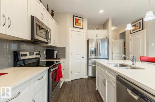 Kitchen featuring white cabinetry, stainless steel appliances, a subway tile backsplash, light-toned countertops, and wood-finish flooring - 12737 205 Street Nw, Edmonton, AB - Indoor Photo Showing Kitchen With Double Sink With Upgraded Kitchen