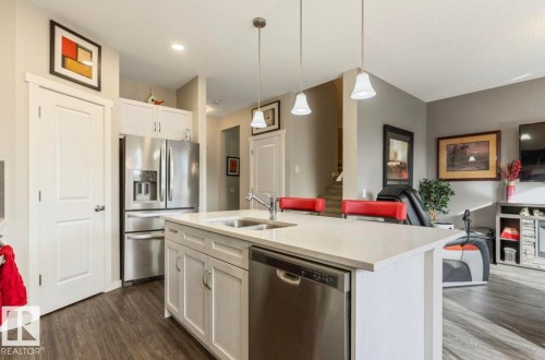 Kitchen island with a light-toned countertop, double basin sink, and pendant lighting - 12737 205 Street Nw, Edmonton, AB - Indoor Photo Showing Kitchen With Double Sink