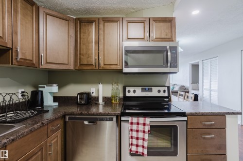 Wood-finish cabinetry paired with dark stone-look countertops - #1002 10149 Saskatchewan Dr Nw, Edmonton, AB - Indoor Photo Showing Kitchen