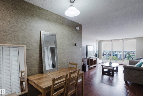 Hardwood-finish flooring, accent wall with textured wallpaper, recessed lighting, and expansive windows - #1002 10149 Saskatchewan Dr Nw, Edmonton, AB - Indoor Photo Showing Other Room