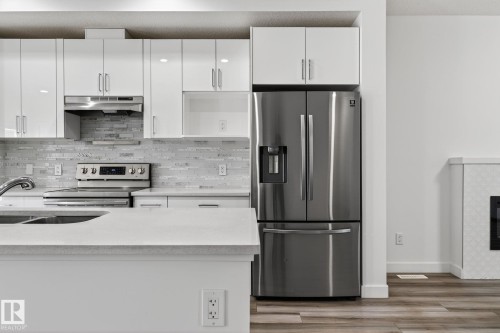 White cabinetry with stainless steel hardware, mosaic tile backsplash, stainless steel appliances, and a light-toned countertop - 4853 Alwood Point(E) Sw, Edmonton, AB - Indoor Photo Showing Kitchen With Upgraded Kitchen