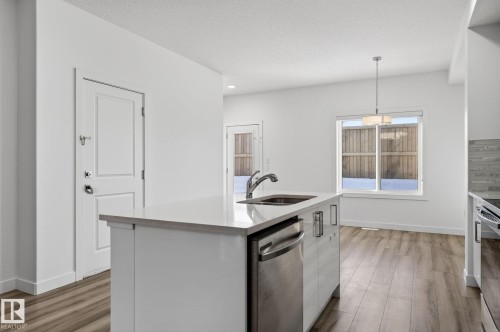 Kitchen island with integrated stainless steel sink and dishwasher - 4853 Alwood Point(E) Sw, Edmonton, AB - Indoor Photo Showing Kitchen