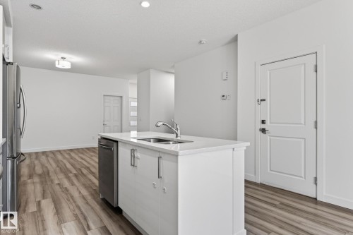 Kitchen island with an undermount sink, stainless steel dishwasher, and white cabinetry - 4853 Alwood Point(E) Sw, Edmonton, AB - Indoor Photo Showing Kitchen With Double Sink