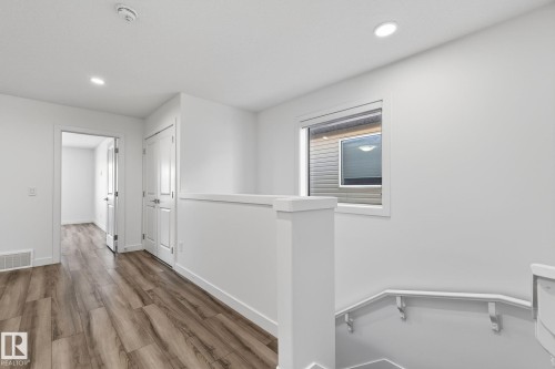 Wood-finish flooring throughout, white walls with recessed lighting, and a contemporary window design - 4853 Alwood Point(E) Sw, Edmonton, AB - Indoor Photo Showing Other Room