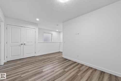 Wood-finish flooring, recessed lighting, double panel doors, and a window with blinds - 4853 Alwood Point(E) Sw, Edmonton, AB - Indoor Photo Showing Other Room