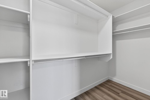White shelving system, integrated hanging rods, and wood-finish flooring - 4853 Alwood Point(E) Sw, Edmonton, AB - Indoor With Storage