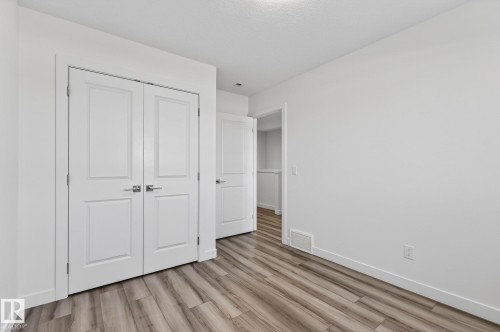 Wide plank wood-finish flooring, white paneled doors, and bright white walls - 4853 Alwood Point(E) Sw, Edmonton, AB - Indoor Photo Showing Other Room