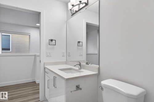 Bathroom featuring a vanity with an integrated sink, polished chrome faucet, and rectangular mirror - 4853 Alwood Point(E) Sw, Edmonton, AB - Indoor Photo Showing Bathroom