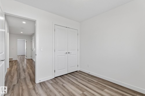 Wood-finish flooring throughout, bright white walls, and a recessed lighting feature in the hallway - 4853 Alwood Point(E) Sw, Edmonton, AB - Indoor Photo Showing Other Room