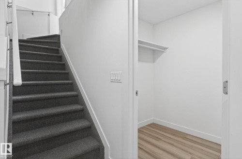 Staircase with dark gray carpeted treads and white handrails - 4853 Alwood Point(E) Sw, Edmonton, AB - Indoor Photo Showing Other Room
