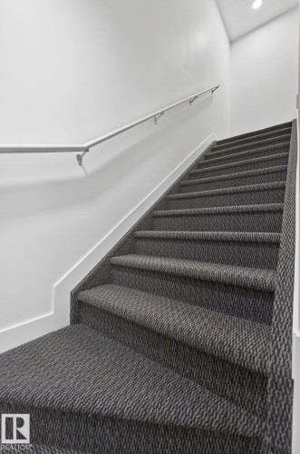 Staircase featuring patterned carpeting, white wall finishes, and a metal handrail - 4853 Alwood Point(E) Sw, Edmonton, AB - Indoor