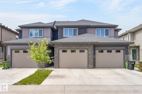 Two-story duplex with attached single-car garages, a stone veneer facade, and concrete driveways - 4853 Alwood Point(E) Sw, Edmonton, AB - Outdoor With Facade