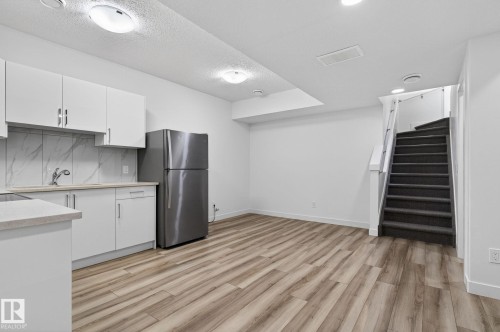 Kitchenette with white cabinetry, stainless steel refrigerator, and wood-finish flooring - 4853 Alwood Point(E) Sw, Edmonton, AB - Indoor Photo Showing Kitchen