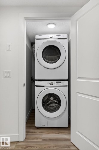 Dedicated laundry closet with stacked appliances and wood-finish flooring - 4853 Alwood Point(E) Sw, Edmonton, AB - Indoor Photo Showing Laundry Room