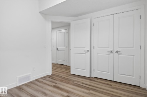 Wood-finish flooring with crisp white walls and trim - 4853 Alwood Point(E) Sw, Edmonton, AB - Indoor Photo Showing Other Room