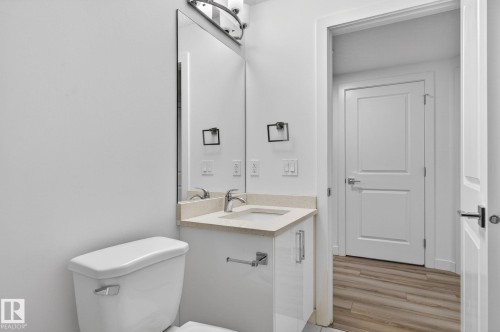White vanity with chrome hardware, an undermount sink, and a light-colored countertop - 4853 Alwood Point(E) Sw, Edmonton, AB - Indoor Photo Showing Bathroom