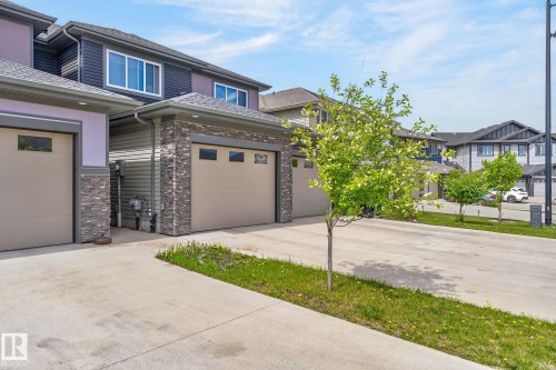 Exterior featuring a stone facade, vinyl siding, and concrete driveways - 4853 Alwood Point(E) Sw, Edmonton, AB - Outdoor