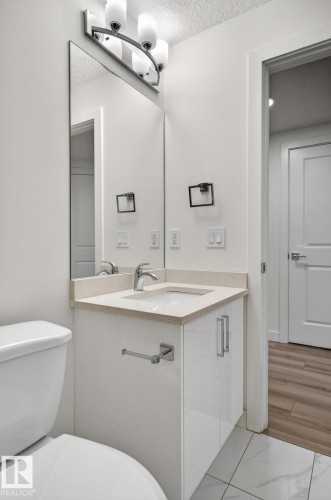 Vanity featuring an integrated sink, polished chrome faucet, and light-colored countertop - 4853 Alwood Point(E) Sw, Edmonton, AB - Indoor Photo Showing Bathroom