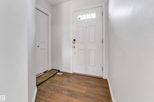Entryway featuring wood-finish flooring, a paneled front door with transom window, and a paneled closet door - 2040 24 Street Nw, Edmonton, AB - Indoor Photo Showing Other Room