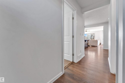 Wood-finish flooring throughout, white trim, and a paneled interior door - 2040 24 Street Nw, Edmonton, AB - Indoor Photo Showing Other Room