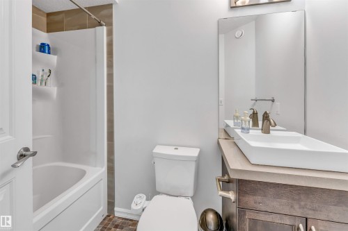 Built-in bathtub with shower surround, contemporary vanity with countertop, rectangular vessel sink, and wall-mounted mirror - 2040 24 Street Nw, Edmonton, AB - Indoor Photo Showing Bathroom