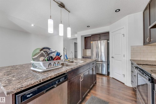 Kitchen with wood-finish flooring, dark wood cabinetry, stainless steel appliances, and a subway tile backsplash - 2040 24 Street Nw, Edmonton, AB - Indoor Photo Showing Kitchen With Double Sink With Upgraded Kitchen