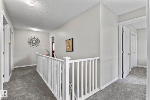 Carpeted hallway featuring white painted banister and trim - 3403 23 Nw, Edmonton, AB - Indoor Photo Showing Other Room