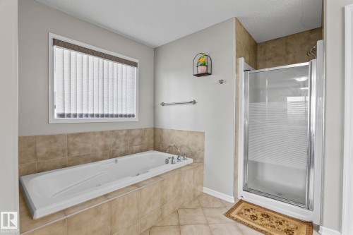 Built-in soaking tub with tile surround, separate glass-enclosed shower, and tiled flooring - 3403 23 Nw, Edmonton, AB - Indoor Photo Showing Bathroom