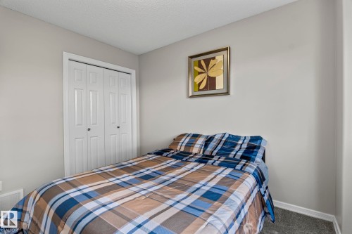 Wall-to-wall carpeting with light gray walls and white bi-fold closet doors - 3403 23 Nw, Edmonton, AB - Indoor Photo Showing Bedroom