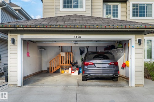 Attached single-car garage with concrete flooring, wood staircase, and built-in shelving - 3403 23 Nw, Edmonton, AB - Outdoor With Exterior
